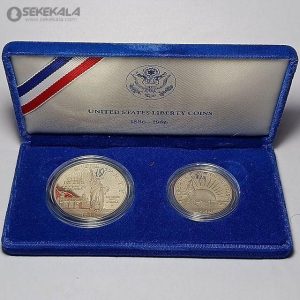 این مجموعه سکه که به مناسبت 100مین سالگرد هدیه مجسمه آزادی از فرانسه به ایالات متحده در سال 1986 ضرب شده، شامل دو سکه نقره‌ای با کیفیت پروف (Proof) است. سکه‌ها در محفظه‌ای زیبا با روکش مخملی آبی و طراحی رسمی "United States Liberty Coins" عرضه شده‌اند. سکه اول یک دلار نقره‌ای است که تصویر مجسمه آزادی به همراه کتیبه "Ellis Island - Gateway to America" و سال 1986 را به نمایش می‌گذارد. طراحی این سکه توسط جک ال. آهر (Jack L. Ahr) انجام شده و با دقت بالایی بر روی سطح نقره‌ای صیقلی ضرب شده است. سکه دوم، یک ربع دلار، با تصویر مجسمه آزادی در برابر نور خورشید و عبارت "In God We Trust" تزئین شده که توسط مینستا (Mint) ضرب شده است.